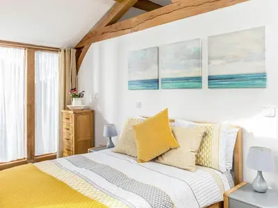 a bedroom with a bed with yellow pillows at The Old Smithy in Bude