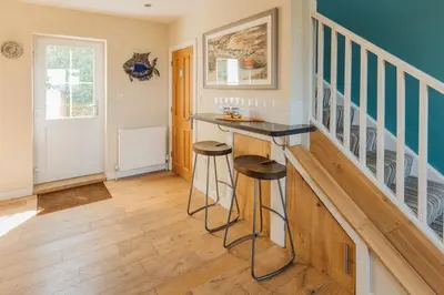 a home bar with stools in a room with stairs at Trewalder in St Merryn