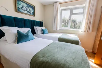 two beds in a room with a window at Trewalder in St Merryn