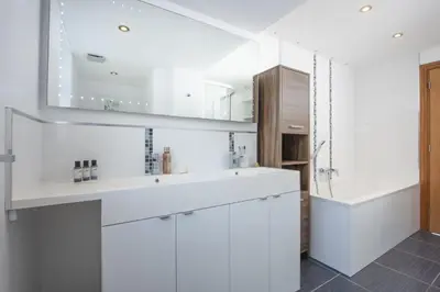 a white bathroom with a sink and a tub at Ocean View, Mawgan Porth - Sea Views - Hot Tub - Free Parking & WiFi in Mawgan Porth