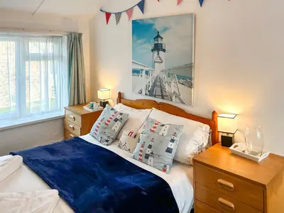 a bedroom with a bed with pillows and a lighthouse at Orchard Cottage in Penzance