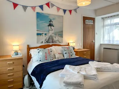 a bedroom with a bed with blue sheets and a lighthouse at Orchard Cottage in Penzance