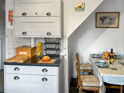 a kitchen with a table and a white cabinet at Orchard Cottage in Penzance