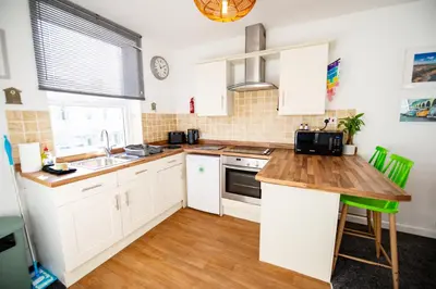 a kitchen with white cabinets and a wooden counter top at Seaside Home with Parking Near Tolcarne Beach in Newquay