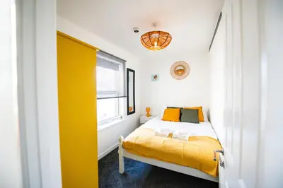 a bedroom with a yellow bed and a window at Seaside Home with Parking Near Tolcarne Beach in Newquay