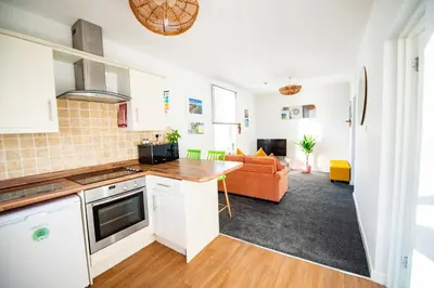 a kitchen and living room with a couch at Seaside Home with Parking Near Tolcarne Beach in Newquay