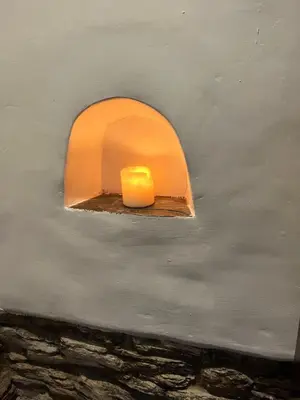 a candle on a wall with a window at Trehaverne Cottage Truro in Truro
