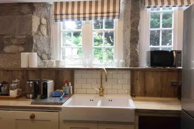 a kitchen with a white sink and two windows at Relaxing historic Roncon's Villa, The Paddock in Perranuthnoe