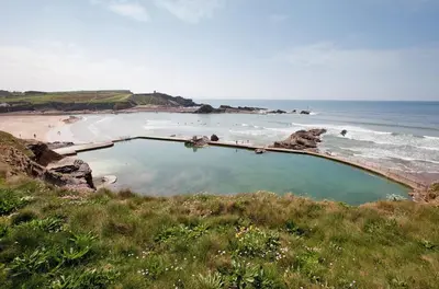 a swimming pool on a beach next to the ocean at 4 Bed in St. Gennys oc-p34626 in Crackington Haven