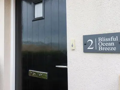 a black door with a sign on the side of a building at Blissful Ocean Breeze in Perranporth
