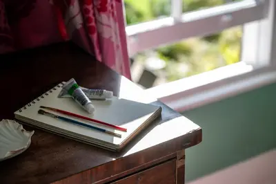 a pen and notebooks on a table next to a window at Beautiful Perranporth country house near the beach in Perranzabuloe