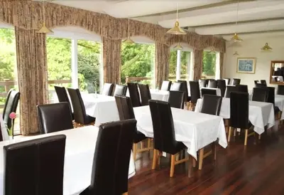 a dining room with white tables and black chairs at Villa 49 Lanteglos Hotel 2 bedroom sleeps 4 in Lanteglos