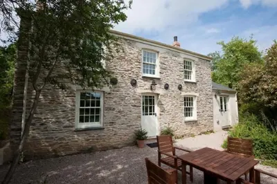 a stone house with a table and benches in front of it at Pencreek in Kea