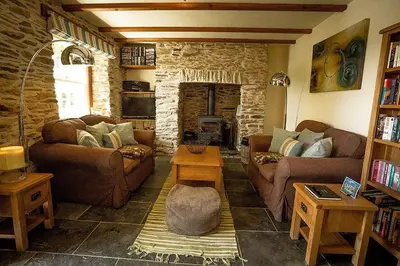 a living room with two couches and a stone fireplace at Pencreek in Kea