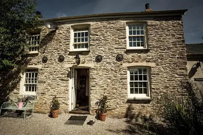 an old stone house with a table and chairs in front of it at Pencreek in Kea