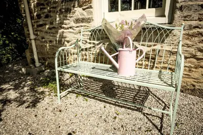 a green bench with a watering can and an umbrella at Pencreek in Kea