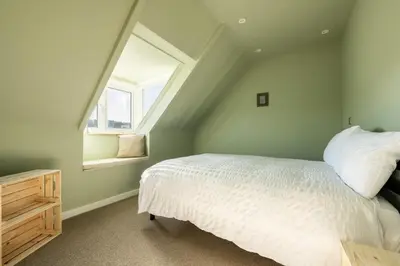 a bedroom with a white bed and a window at Spacious House Sea Views Opposite Beach in Newquay