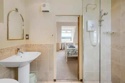 a bathroom with a sink and a glass shower at Beautiful Home with Pool Overlooking Camel Estuary in Roche