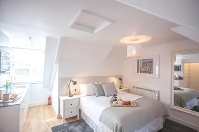 a white bedroom with a bed with a tray of fruit on it at The Attic, Tre-Pol-Pen in St Ives