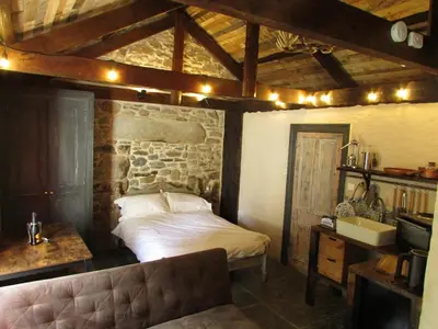 a bedroom with a bed and a stone wall at Cornwall Log Burner no cleaning fee in Camborne