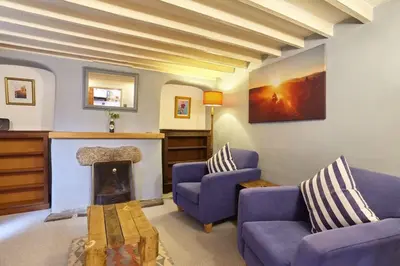 a living room with two purple couches and a fireplace at Cornish Cottage St Agnes free parking and garden in St. Agnes