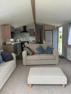 a living room with two couches and a kitchen at Cosy three bedroom holiday home in Parkdean Newquay in Newquay