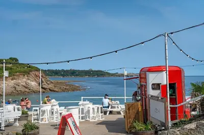 a red gas station next to a beach with people at Scandi Style Apartment in Central Falmouth in Falmouth