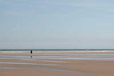 a person walking on a beach with the ocean in the background at Stylish Apartment Garden with Beautiful Sea Views in Newquay