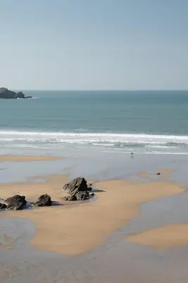 a beach with rocks in the sand and the ocean at The Old Post Office Private Parking & Garden in Newquay