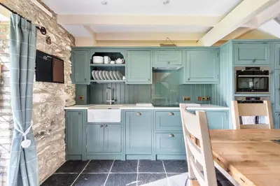 a kitchen with blue cabinets and a wooden table at 2 Bedroom Cottage Close to Perranporth Beach in Roche