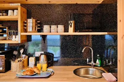 a kitchen counter with a sink and a plate of food at Finest Retreats - Demelza Shepherds Hut in Grade