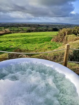 a bath tub filled with water next to a field at Finest Retreats - Demelza Shepherds Hut in Grade