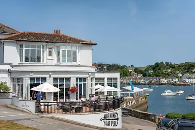 a restaurant with tables and umbrellas next to a body of water at Penthouse Apartment with Sea Views Falmouth in Falmouth
