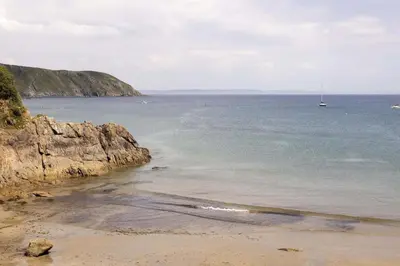 a view of a beach with a boat in the water at Cottage & Boatshed in Gorran Haven Private Parking in Gorran Haven