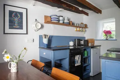 a kitchen with a table and a blue cabinet at Old Cottage 1 min from the sea! Crackington Haven in Crackington Haven