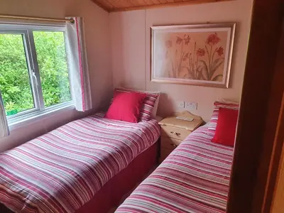 two beds in a small room with two windows at The Retreat in Polperro