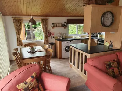 a kitchen and living room with a table and a clock at The Retreat in Polperro