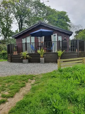 a cabin with an umbrella and a porch at The Retreat in Polperro