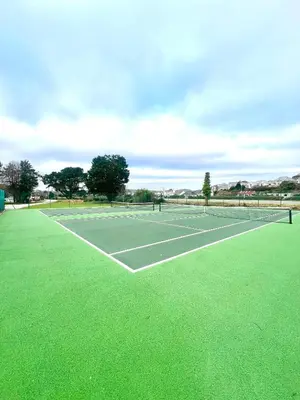 a tennis court with green grass on it at The Crab Shack in Tywardreath