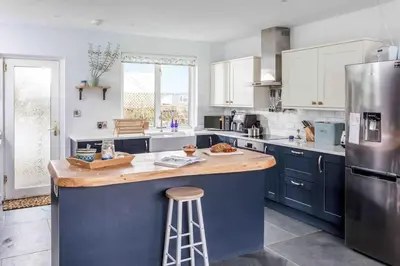 a kitchen with blue cabinets and a wooden counter top at Parkland Place - Spacious Newquay family holiday home, parking, log burner, dog friendly in Saint Columb Minor