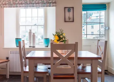 a dining room with a wooden table and chairs at A Room In Coombe in Truro