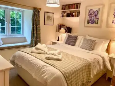 a bedroom with two beds and a window at Hollyhocks Cottage surrounded by beautiful Cornish countryside. in Helland