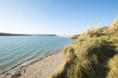 a sandy beach next to a body of water at Hay Barn St Breock beautiful countryside views in Wadebridge