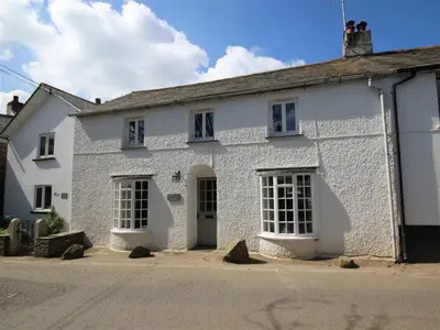 a white brick building with a green door at Fernleigh Cottage near the North Cornish beaches in Saint Mabyn