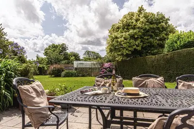 a table and chairs on a patio in a garden at Fourways near the golden sands of Marazion in Leedstown