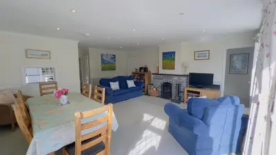 a living room with a table and blue chairs at Seamist Rock - on the north coast of Cornwall in Roche