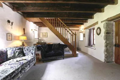 a living room with a couch and a staircase at The Barn in Camelford