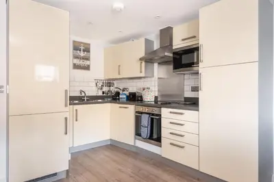 a kitchen with white cabinets and stainless steel appliances at Zephyr in Fowey