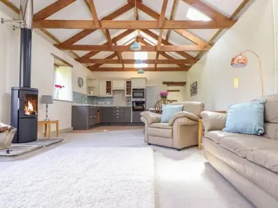 a living room with a couch and a fireplace at Hideaway Barn in Germoe
