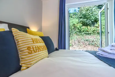 a bed with yellow and blue pillows and a window at Trewhiddle Cottage 41 - 1 Bed Ensuite in St Austell